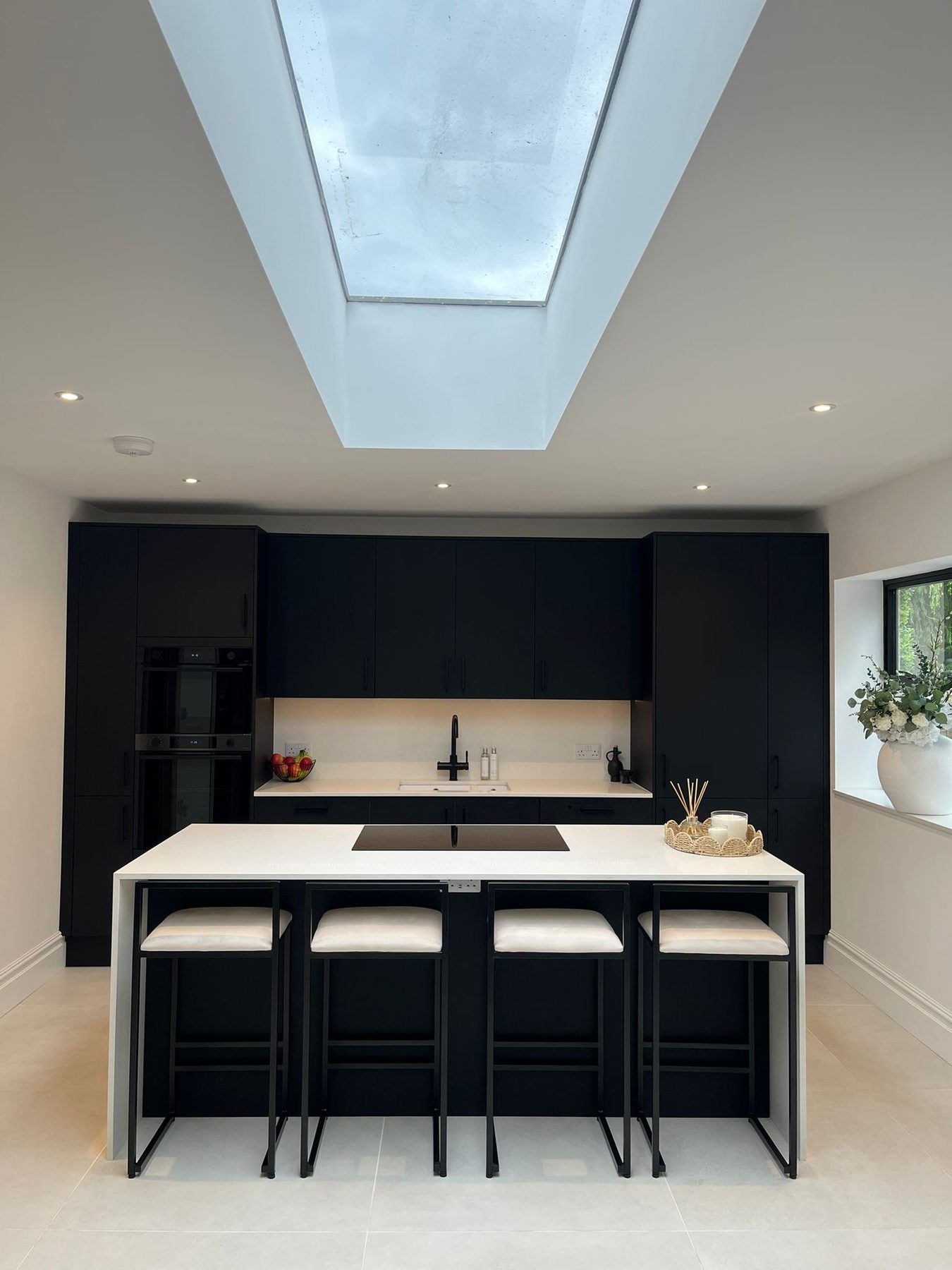 Dark kitchen with white island and rooflight